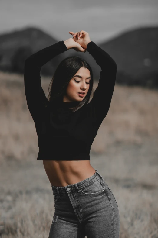 woman stretching in a grassy field with her arms outstretched