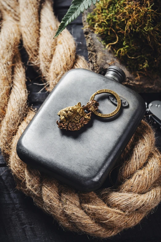 a metal flask, keyring and rope on a table