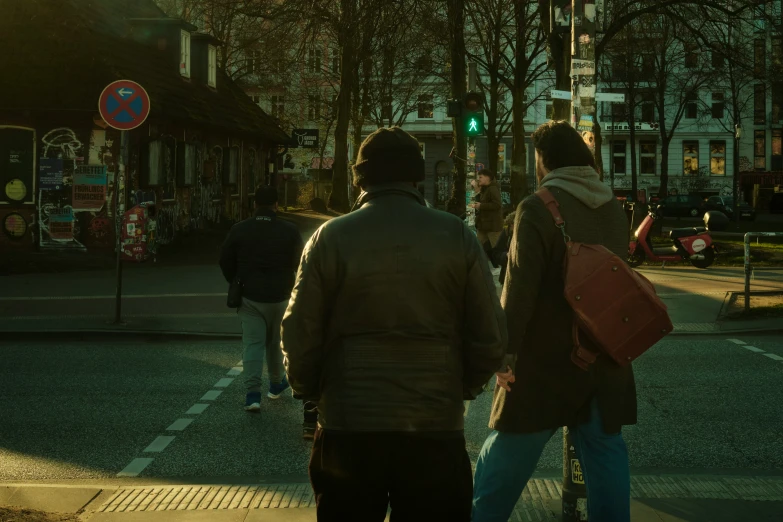 a man and woman walking at an intersection in the sunset