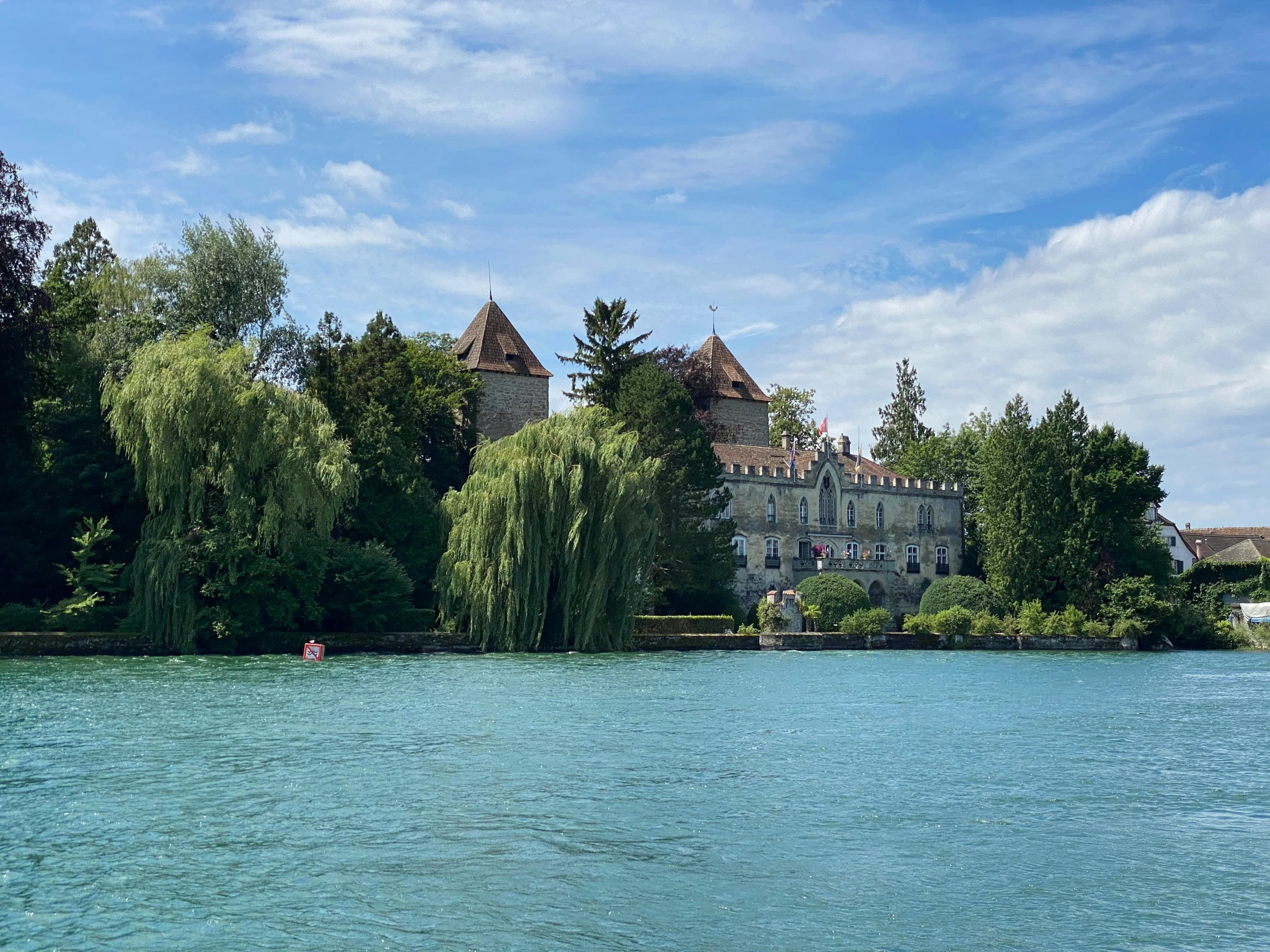 a lake with water and trees and some buildings