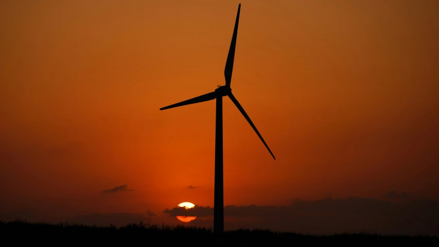 the sun shining behind two wind mills