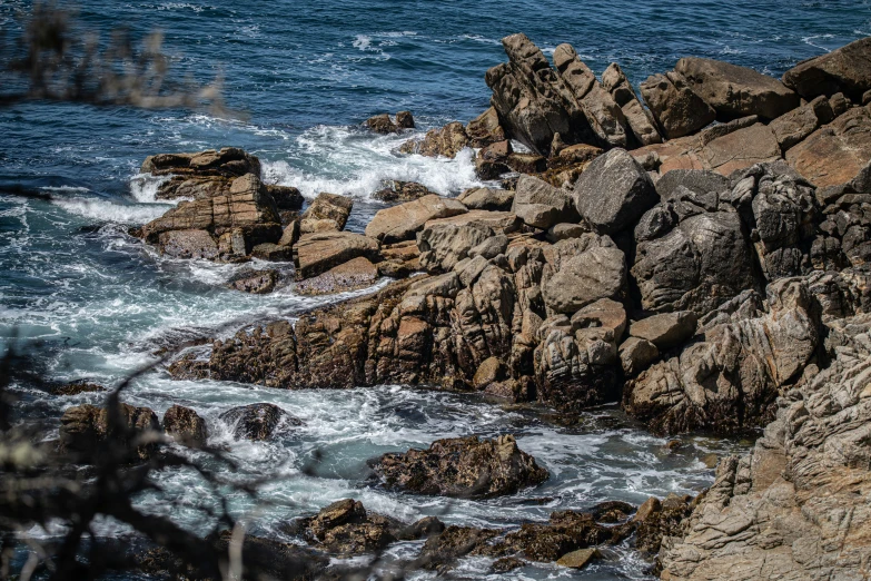 a rocky shore has small waves crash on the rocks