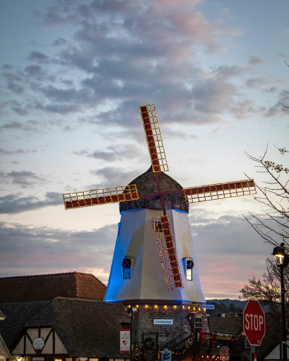 a blue windmill is lit up at dusk