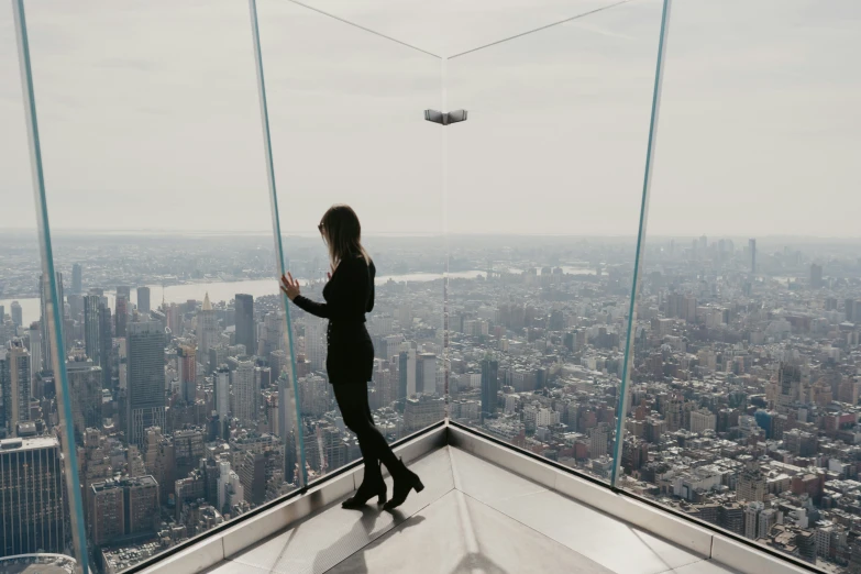 woman on ledge above city buildings with sky line