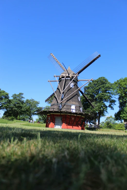 an old, traditional windmill still stands on the grass