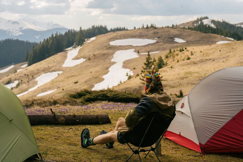 a person sitting in front of a tent in a field