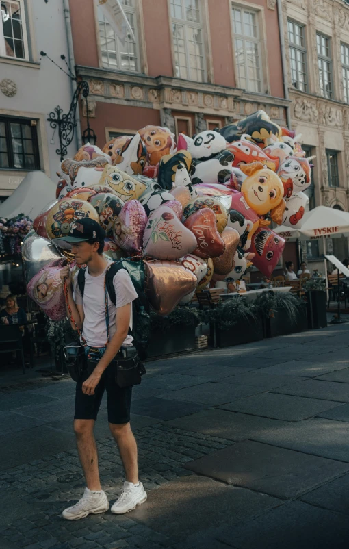 a man walking on the street holding onto several huge balloons