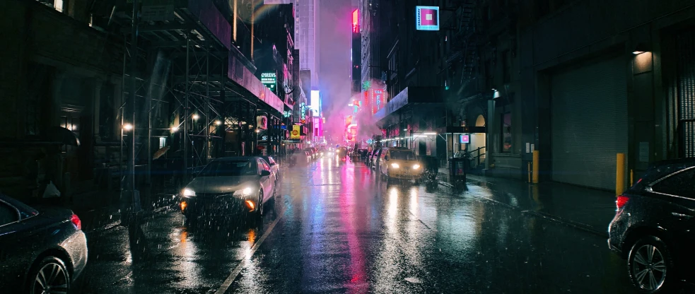 a rain covered city street with cars parked on the side