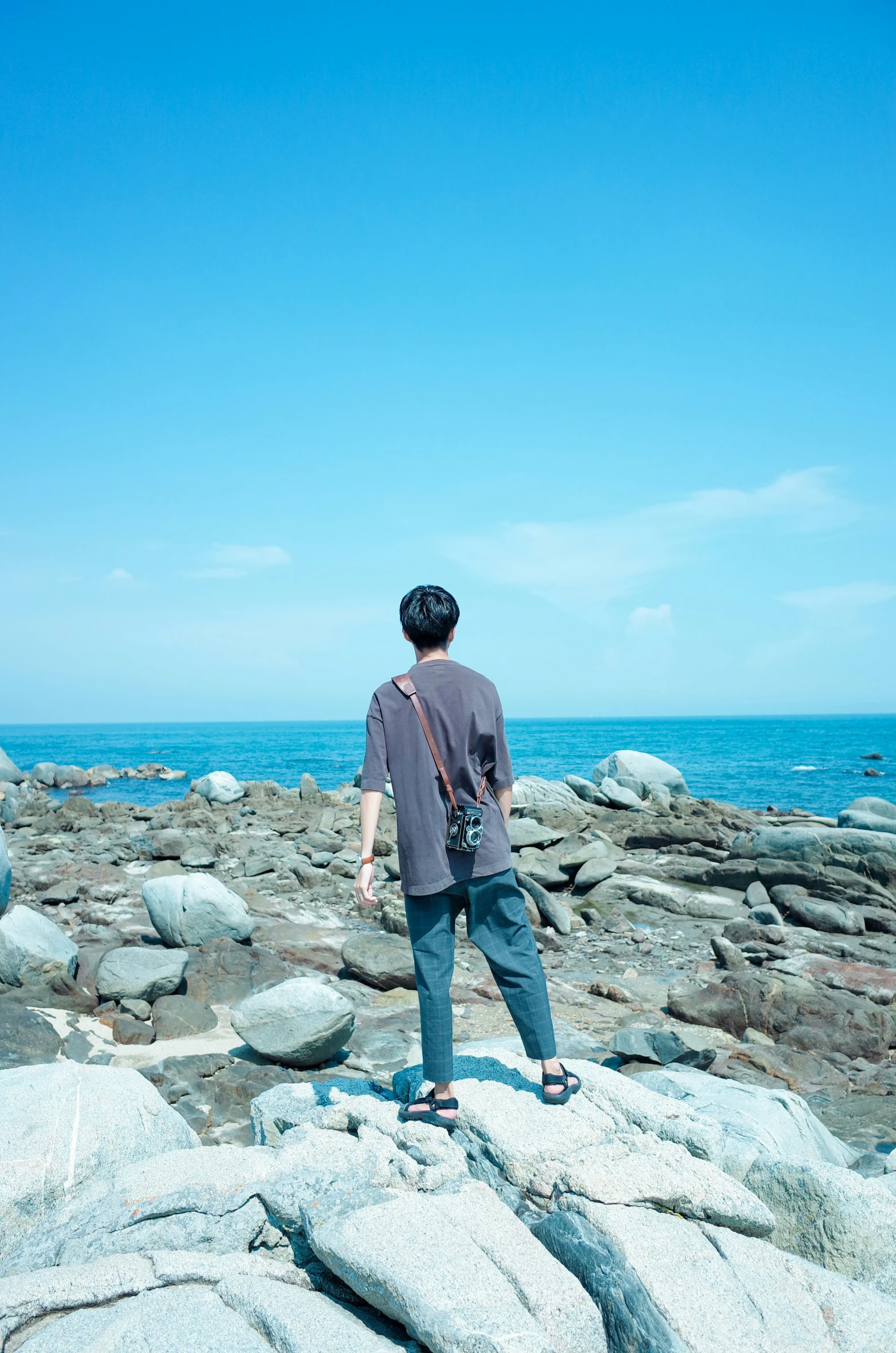 the man is standing on rocks near the water