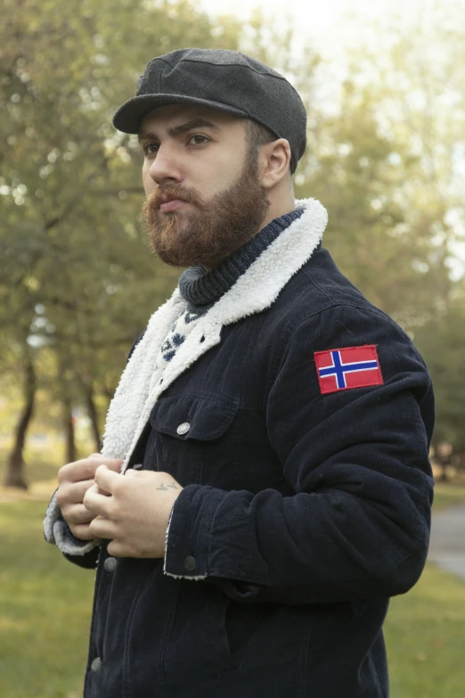 man standing outside in a park wearing a jacket with the flag of norway on it