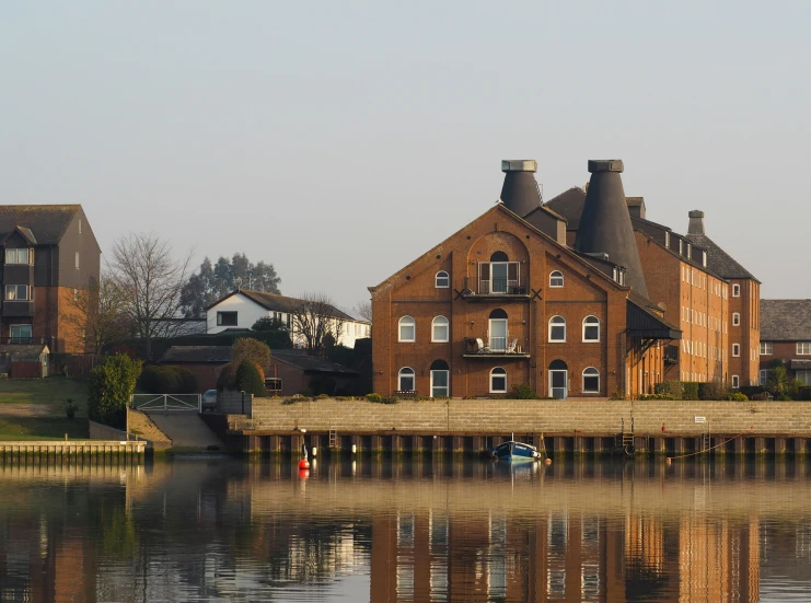 large brick building next to waterway with house in back