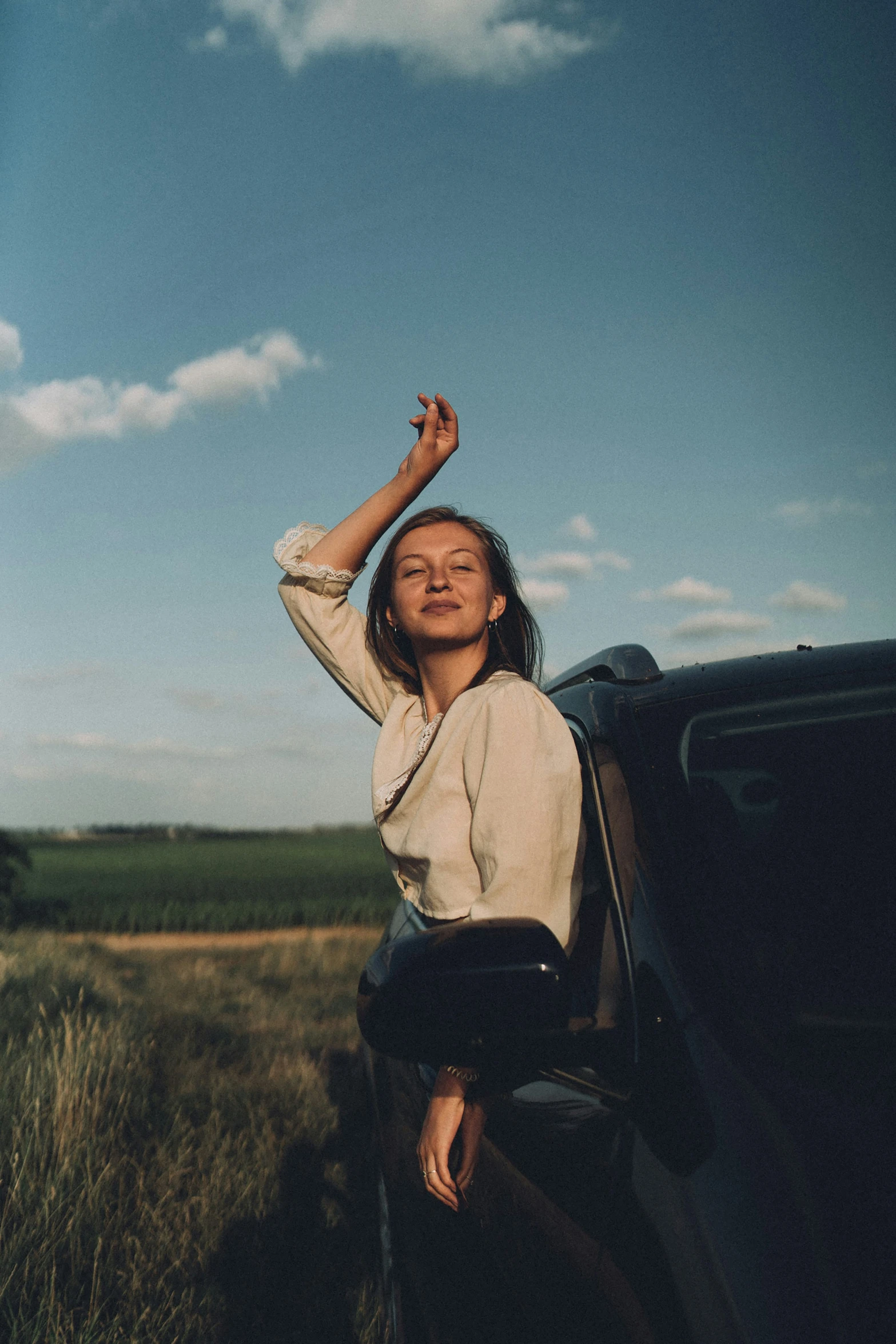 a girl leans out the window of a car in the country