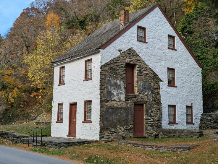 an old white house is sitting next to a road