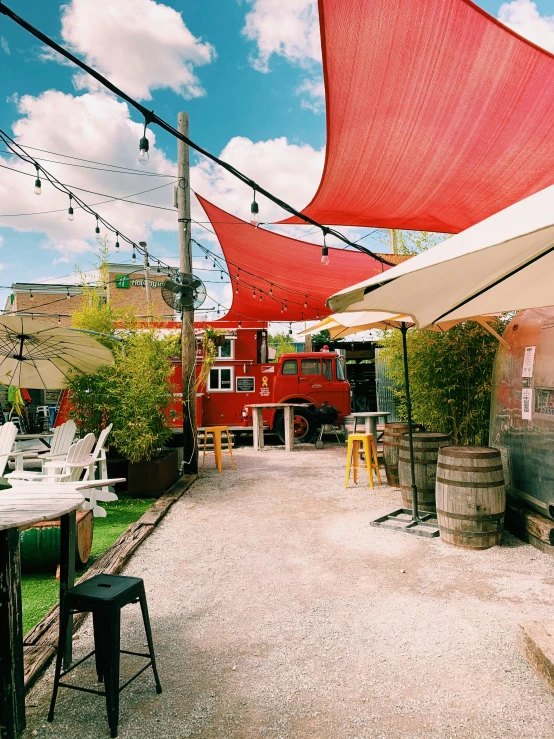 a row of red umbrellas are outside near tables and chairs