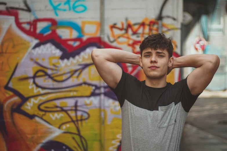 a man stands in front of a wall with graffiti on it