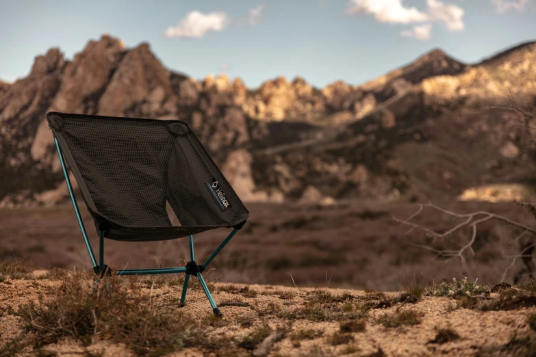 a chair on the ground near mountains under a cloudy blue sky