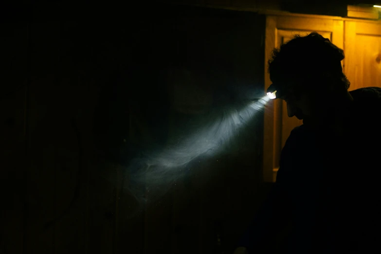 a silhouette of a man holding a flashlight