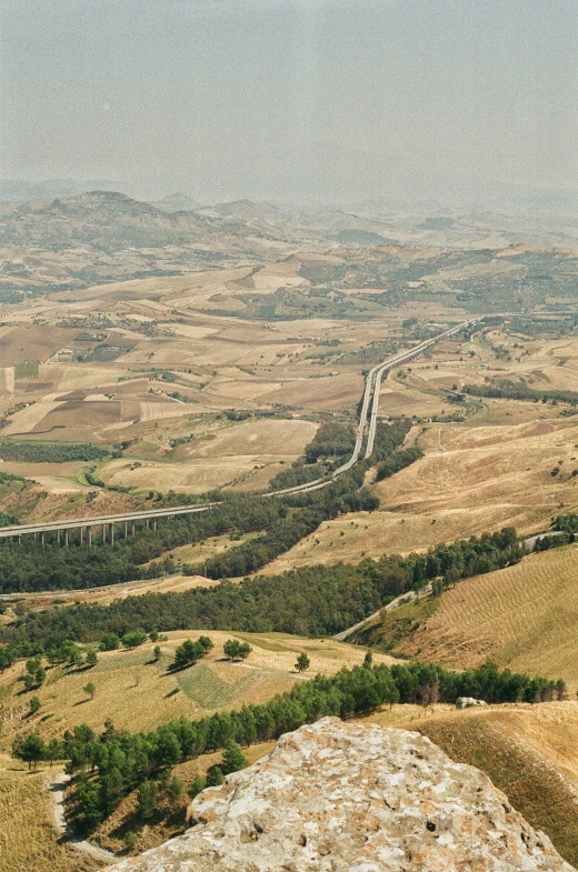 a view from the top of a hill, with a stretch of road on the far side