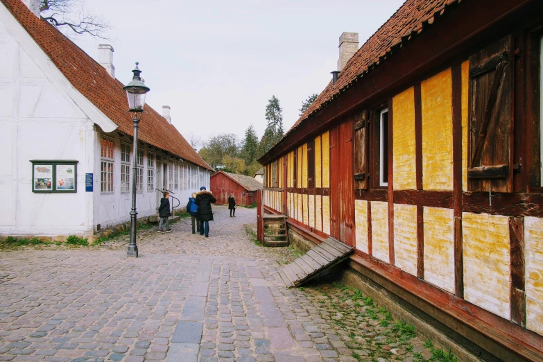 people walking down a brick street past buildings