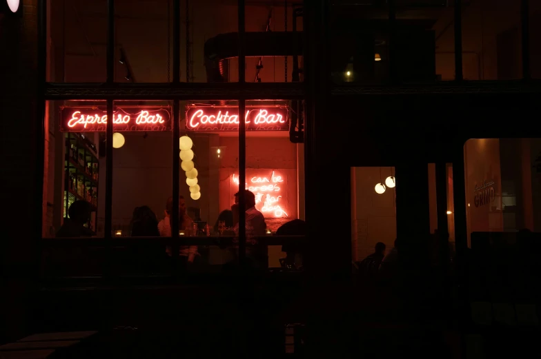 people are sitting outside at night in front of the restaurant