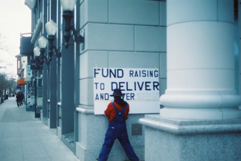 a woman walks down a city street past a sign