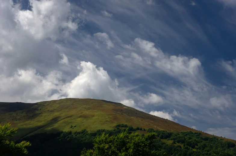 a sky with lots of clouds next to a hill