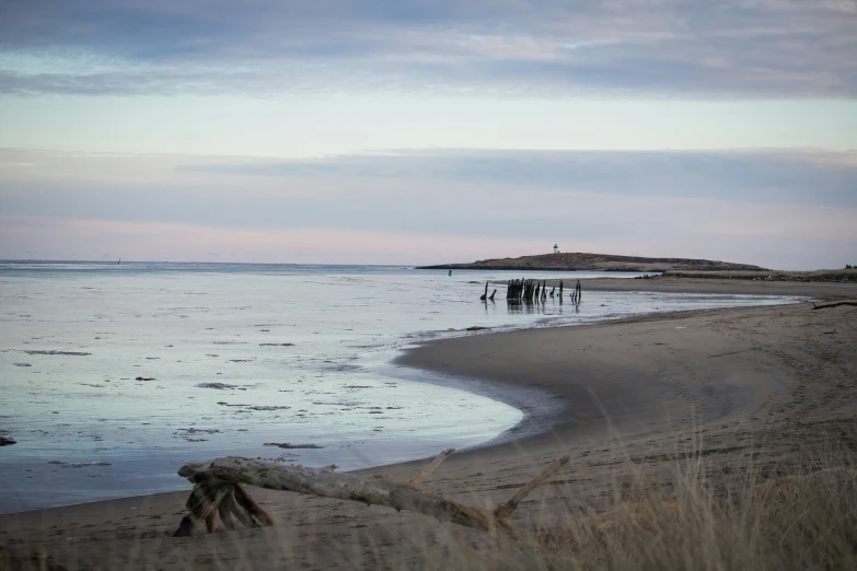 three people stand on the beach near the water