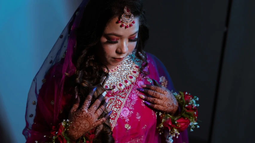 a bride in her wedding gown is placing jewels on her neck