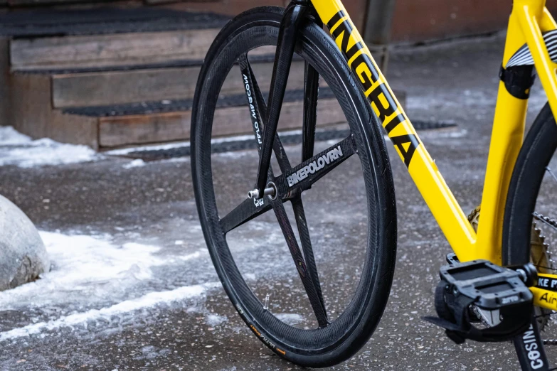 the rear ke on a yellow bicycle is sitting outside