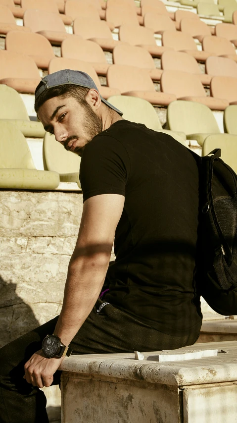 a man in black jacket sitting down with his backpack