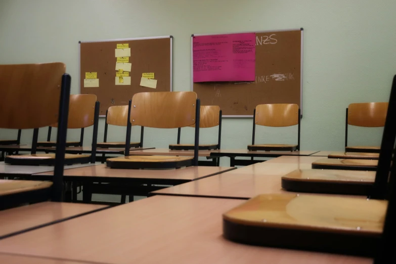 classroom desks with paper taped to the back and on the wall