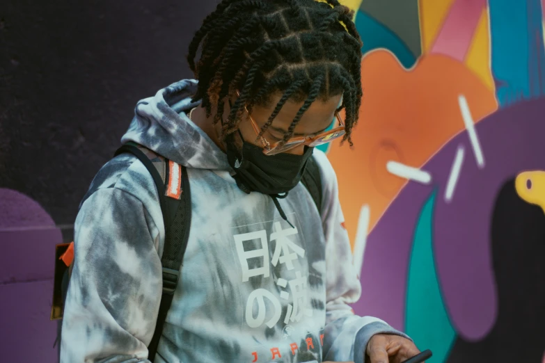 a boy with dreadlocks looks at his cellphone