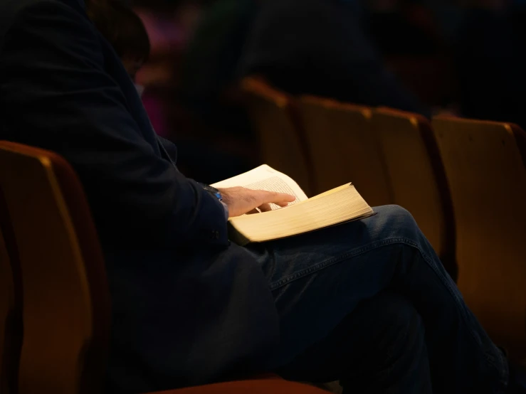 a person is sitting in a chair while holding a notebook