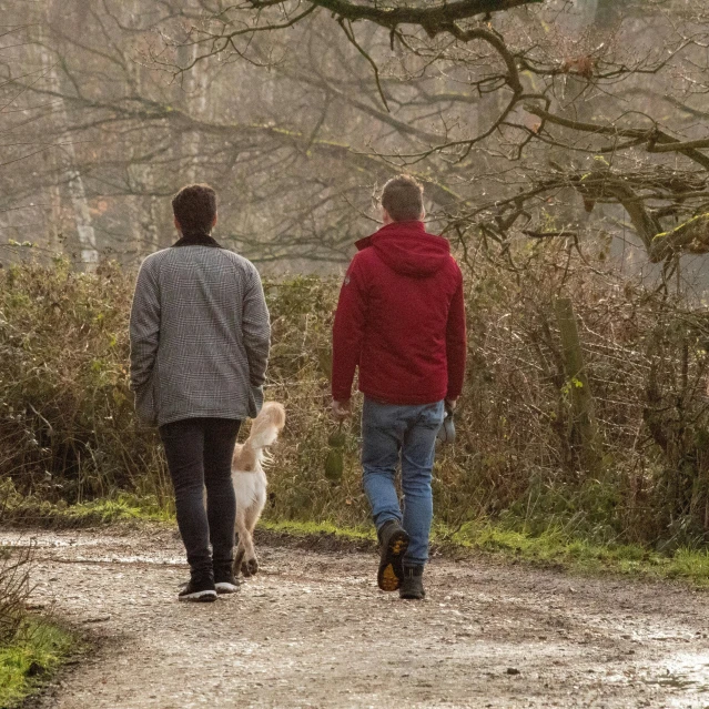 a man and a woman walking down a path with their dog