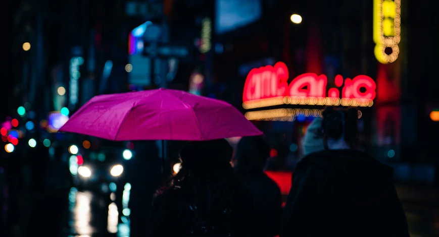 a person under an umbrella walking down the street at night