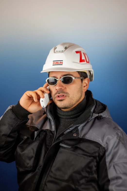 a man with a hard hat and goggles on holding a cell phone