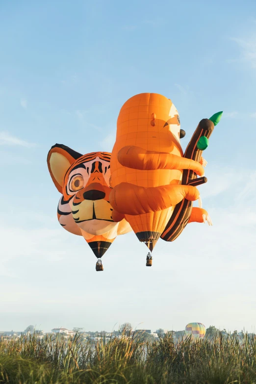 an orange cat balloon flies across the sky