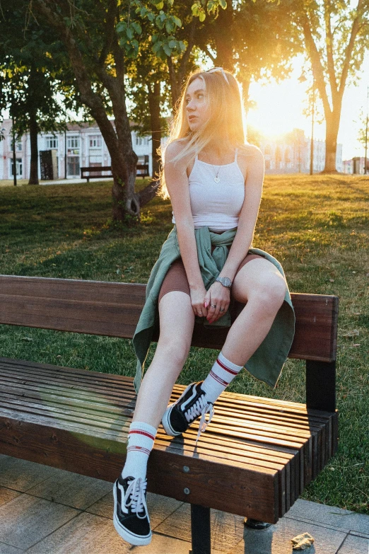 woman sitting on park bench while sun shines through trees