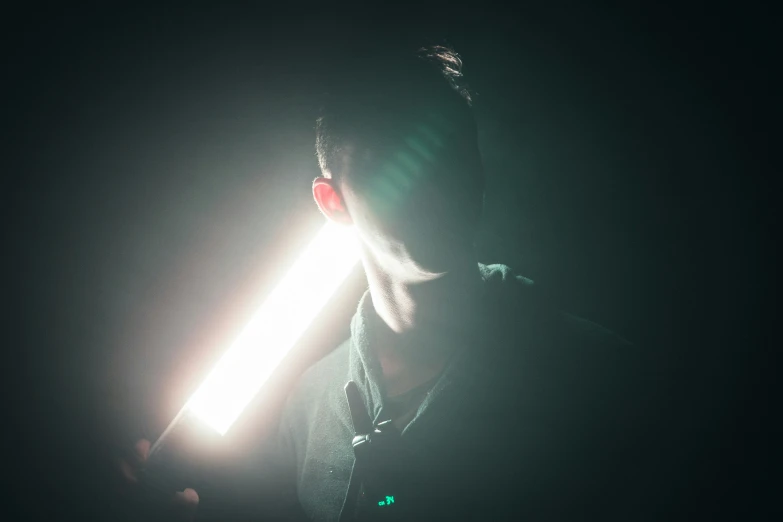 a man standing with a light saber lite up his face