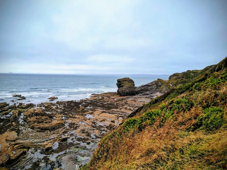 the rocky cliff faces the ocean as the tide moves in