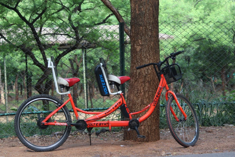 the red bicycle is  to a fence