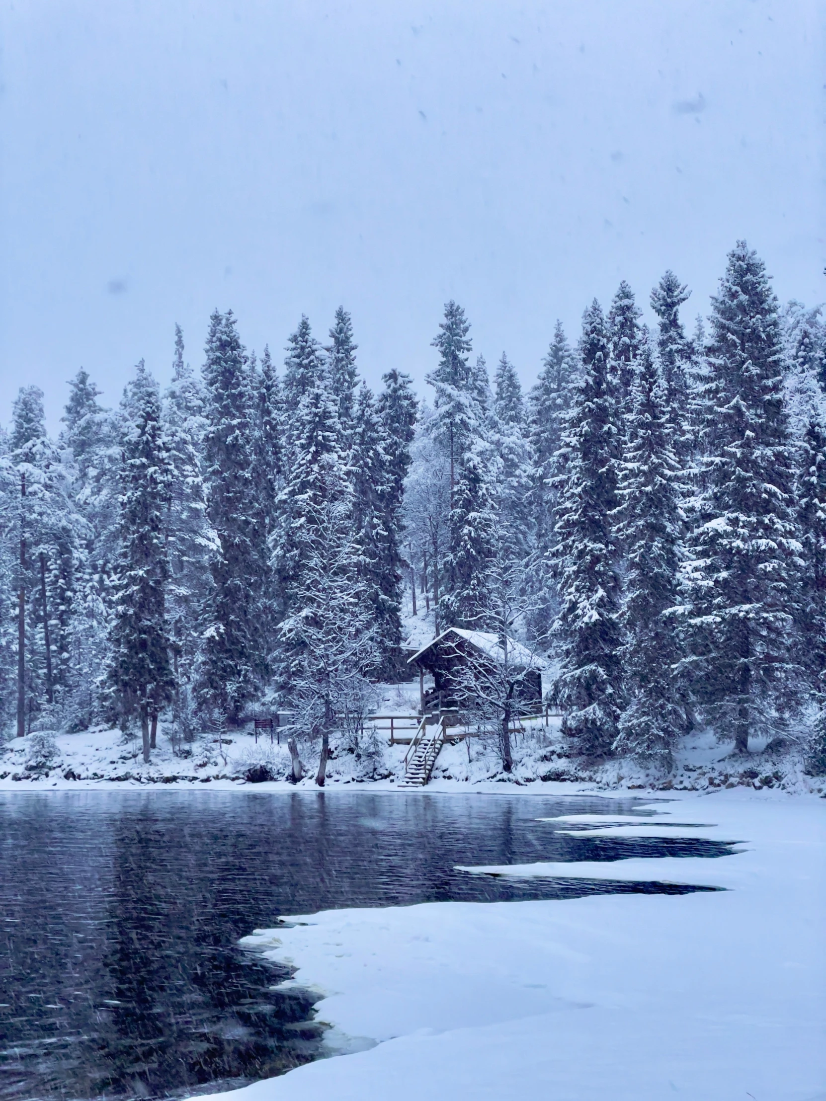 a cabin nestled on a river is shown in the snow