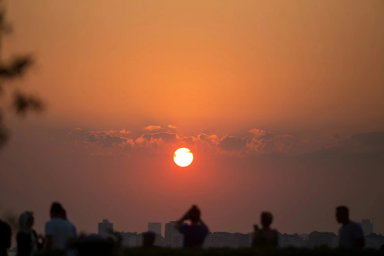 a group of people that are standing near the sunset