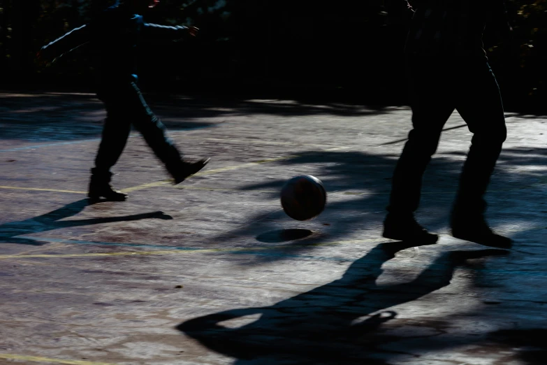 two people in shadows walking towards an upside down ball