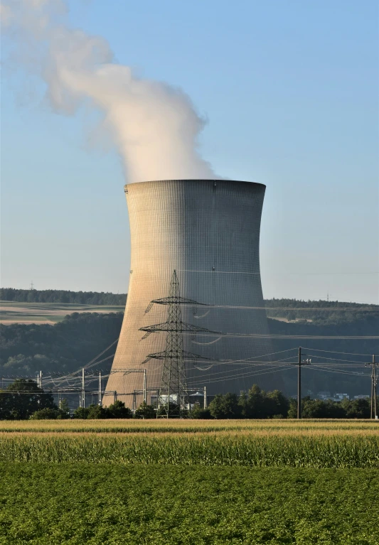 a large cooling tower in the background with smoke coming out