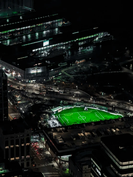 a large field of soccer sitting in a city at night