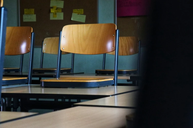 a room filled with lots of wooden chairs sitting on top of a table