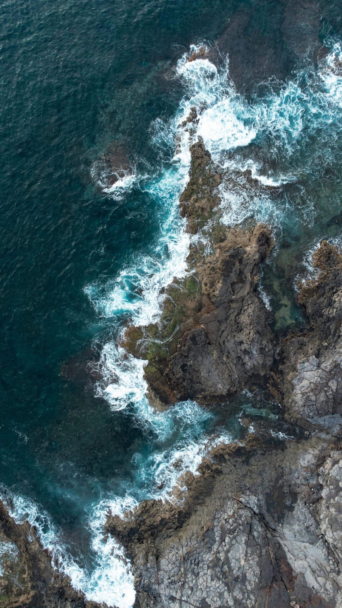 some water is coming out of the ocean and its foamy rocks