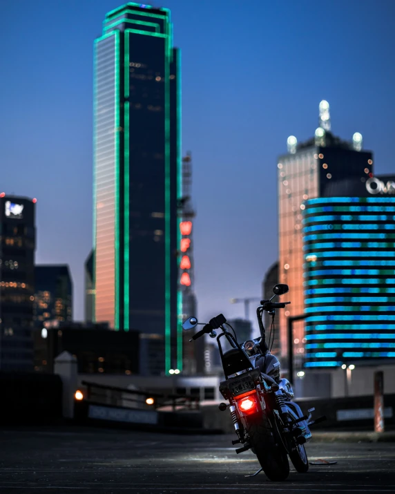 motorcycle parked in city at dusk with tall buildings