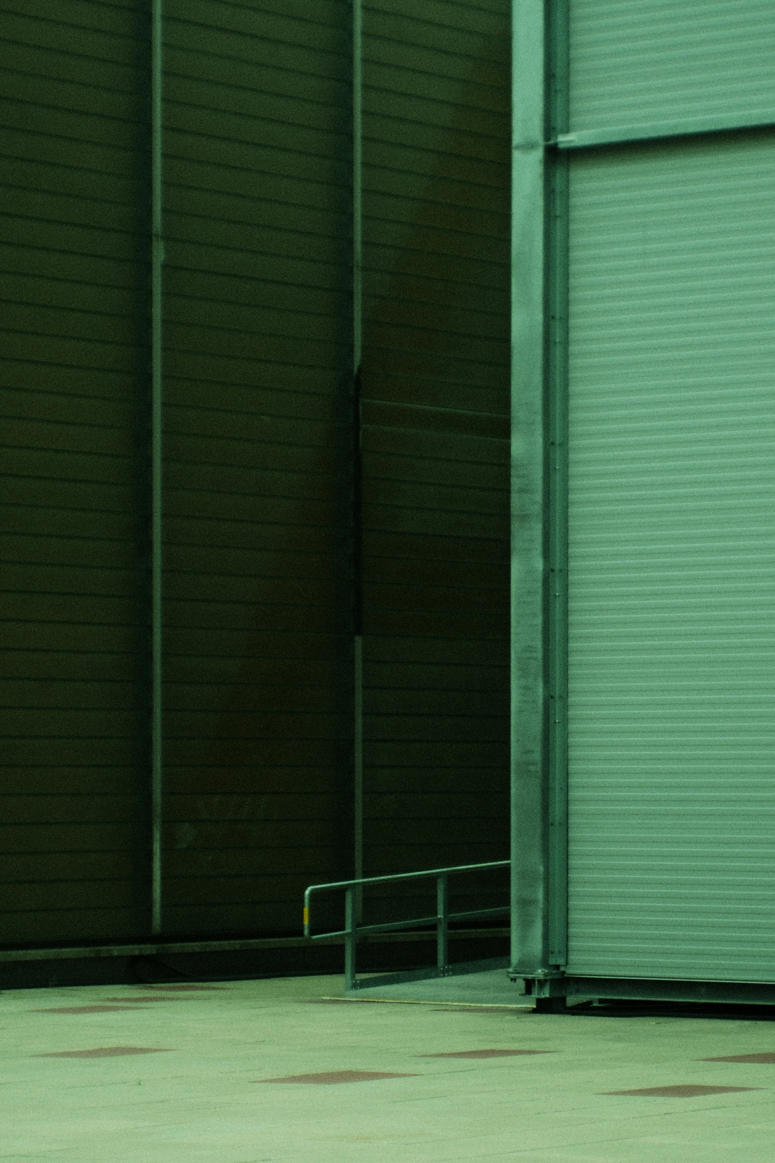 a man stands against a green wall with his foot up on the rail